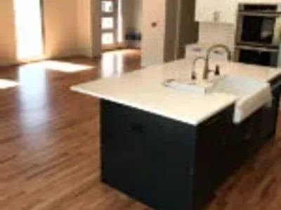 new hardwood floors in updated kitchen with black cupboards and white countertops