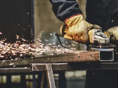 Worker grinding metal with sparks flying.