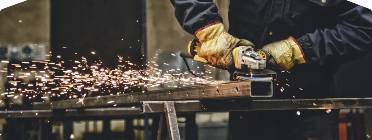 Worker grinding metal with sparks flying.