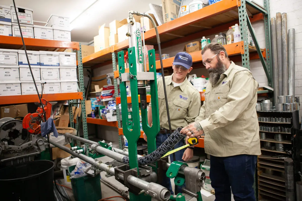 2 electricians measuring and cutting pipes