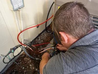 A heating and cooling technician from Bill's heating and AC is brazing an air conditioning condenser line set.