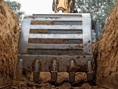 Excavator os scooping a tench for city sewer services.