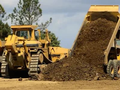 Dumptruck unloading near a roadway for preparation.