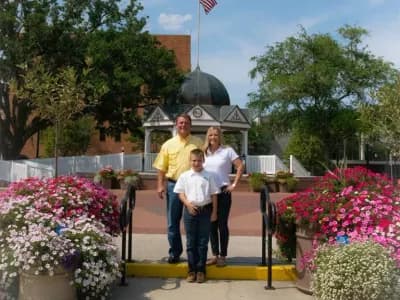 Family posing outdoors among vibrant flowers.