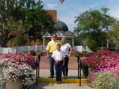 Family posing outdoors among vibrant flowers.